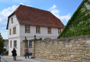 Renoviertes historisches Haus mit hoher Natursteinmauer.