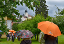 Nicht immer war das Wetter schön. Die bunten Regenschirme der Kommissionsmitglieder bilden beim Rundgang einen Kontrast zu den grünen Bäumen und dunklen Wolken.